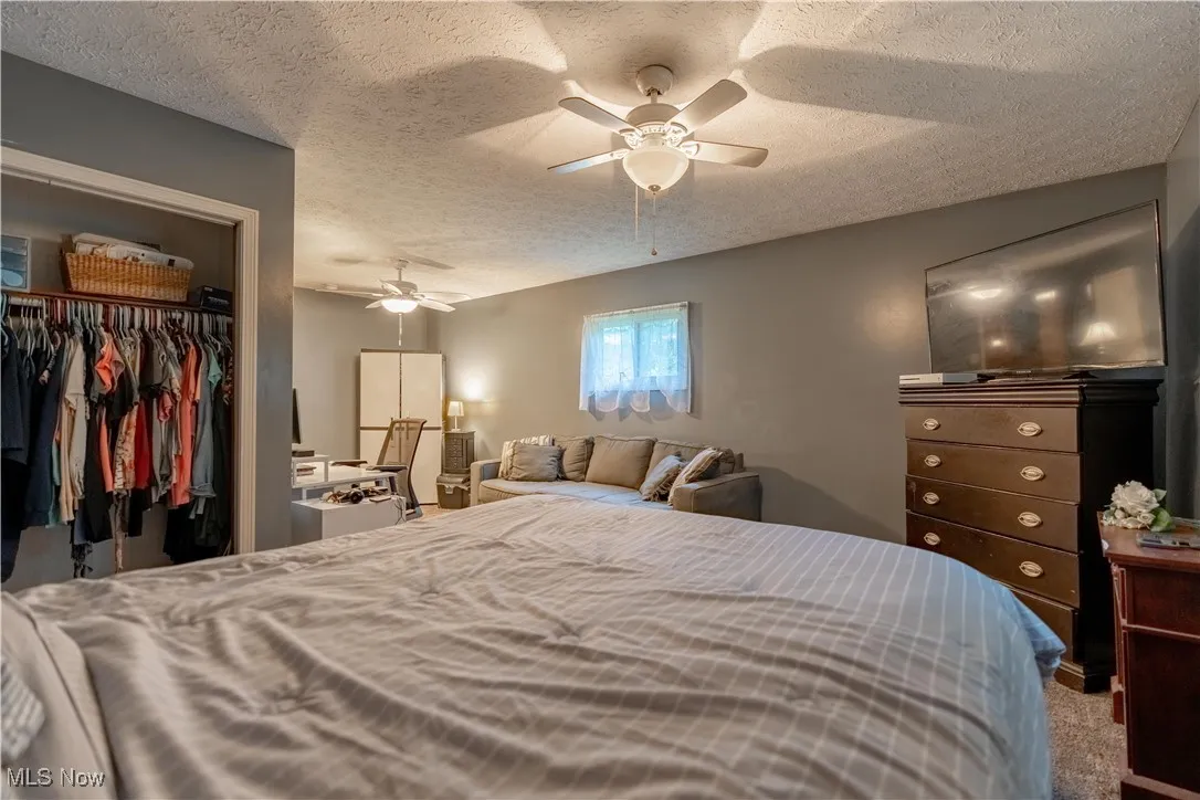 Bedroom with a textured ceiling, a ceiling fan, and carpet