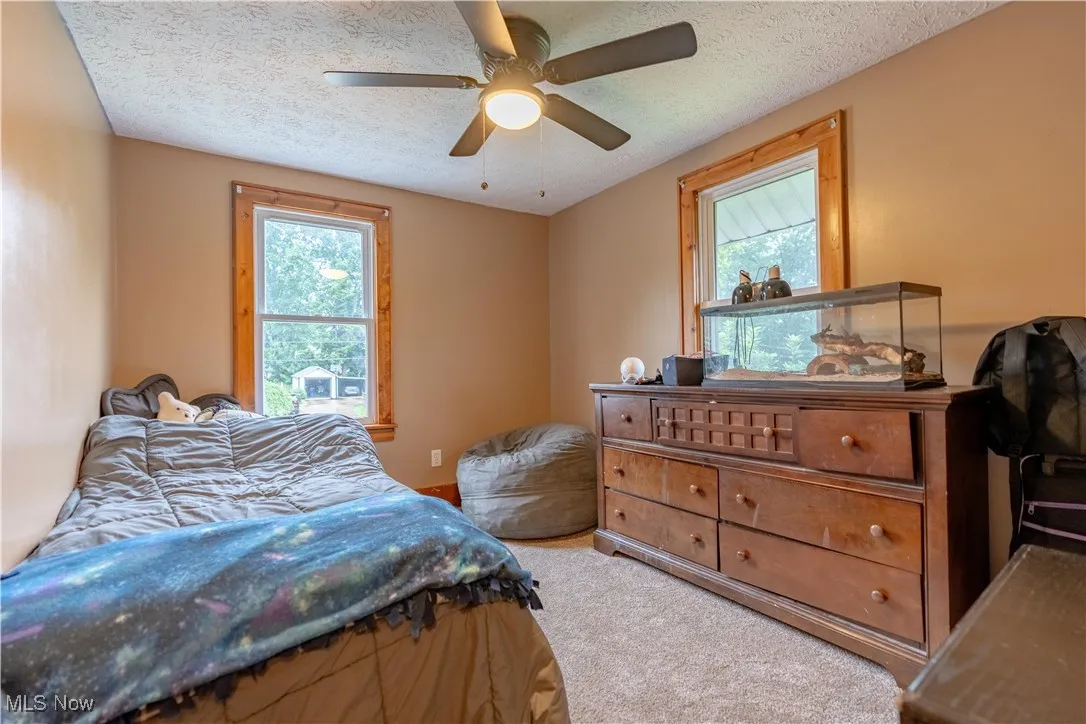 Carpeted bedroom featuring a textured ceiling and a ceiling fan
