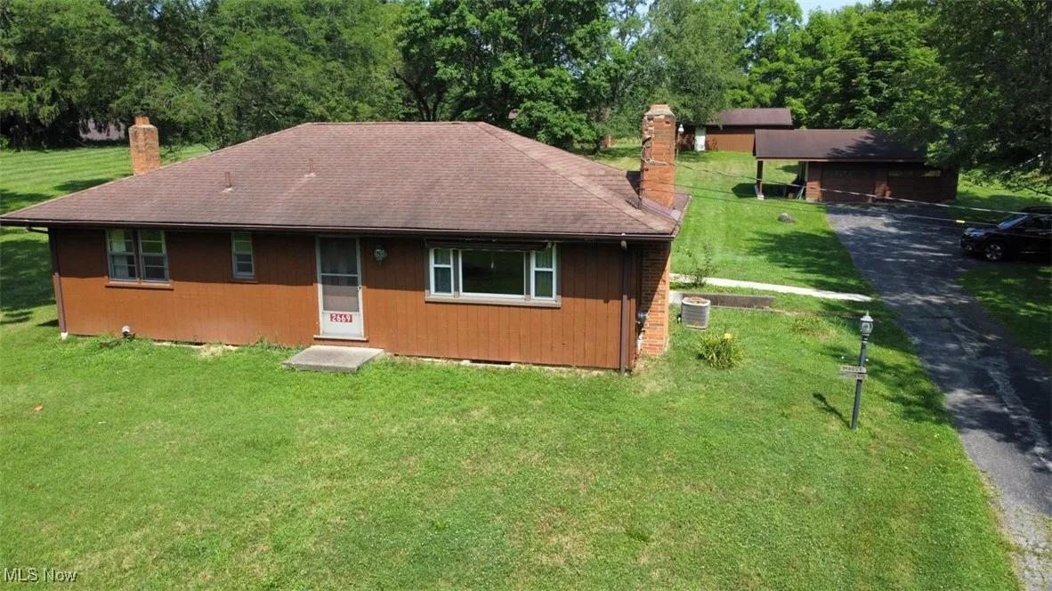 Front of property featuring a chimney, a yard, and a shingled roof