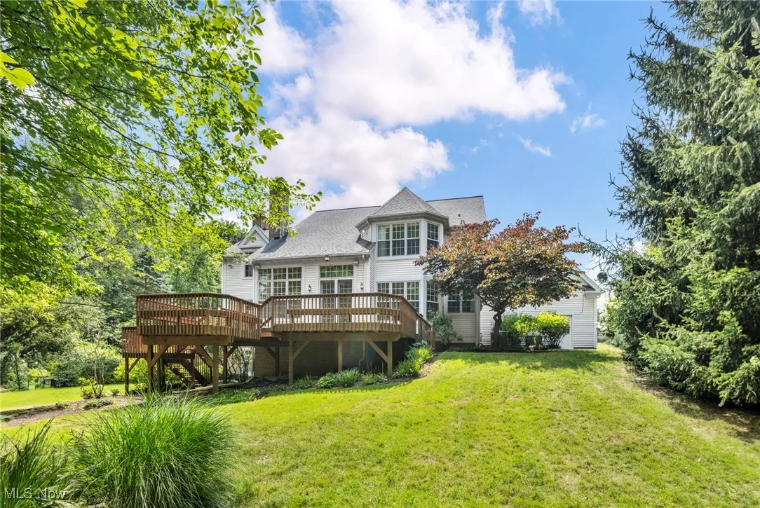 Back of house with a deck and a lawn