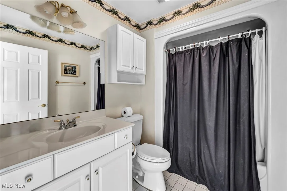 Bathroom with vanity, tile patterned flooring, and a shower with shower curtain