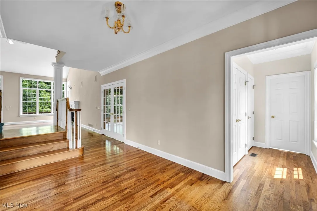 Empty room featuring light wood-style floors, ornamental molding, and stairway