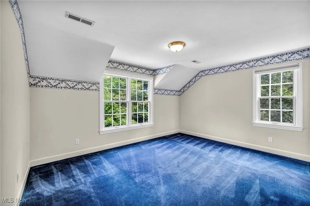 Additional living space with carpet floors and vaulted ceiling