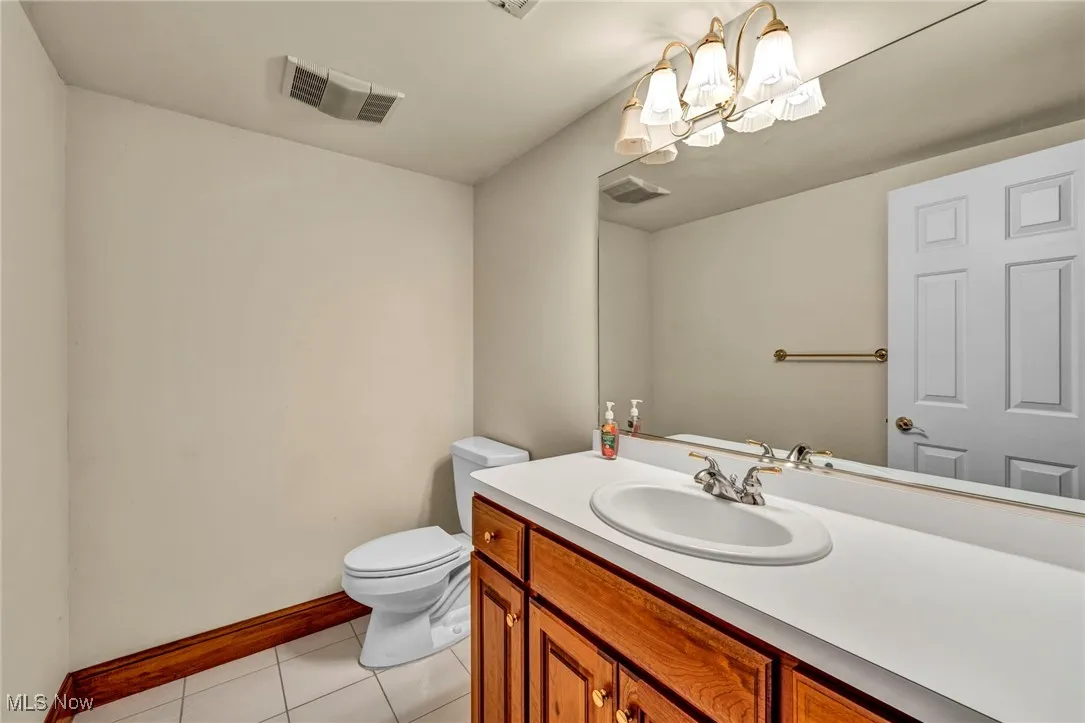 Half bathroom with vanity, tile patterned flooring, and a chandelier