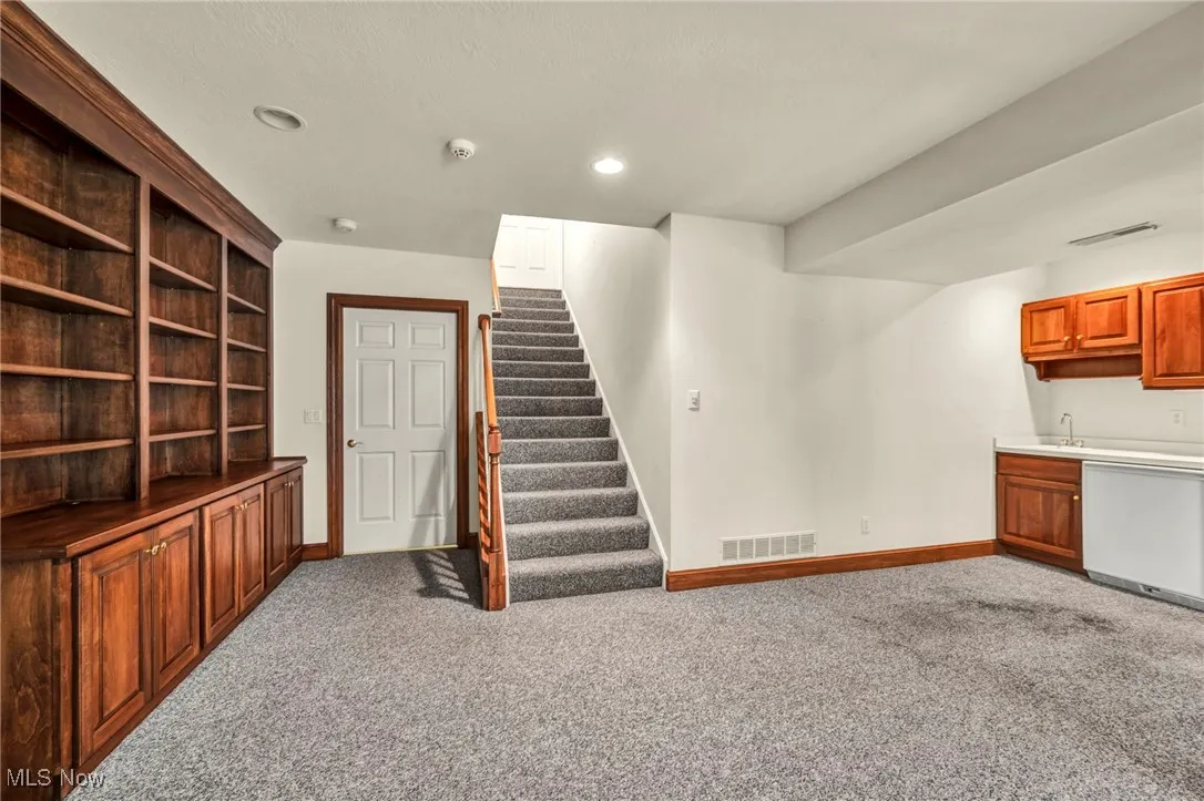 Unfurnished living room featuring carpet floors, stairs, and recessed lighting