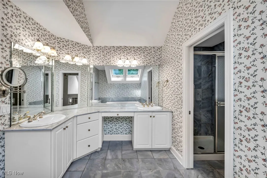 Bathroom featuring wallpapered walls, a shower stall, and vanity