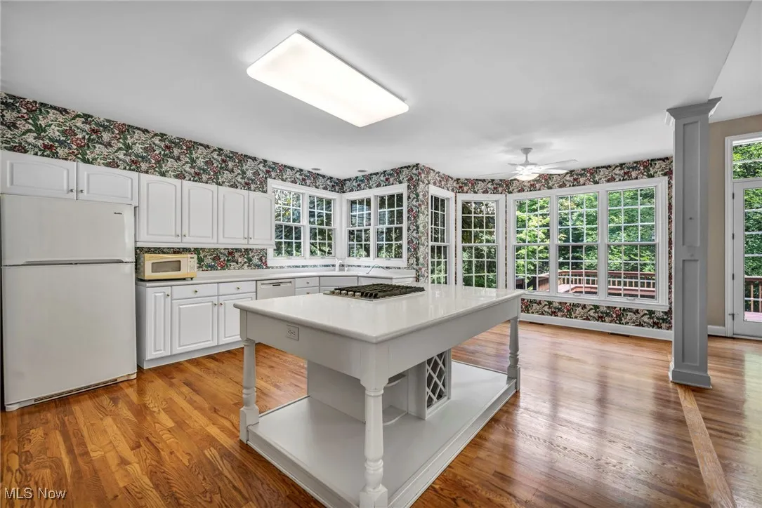 Kitchen featuring wallpapered walls, white appliances, light countertops, white cabinets, and ceiling fan