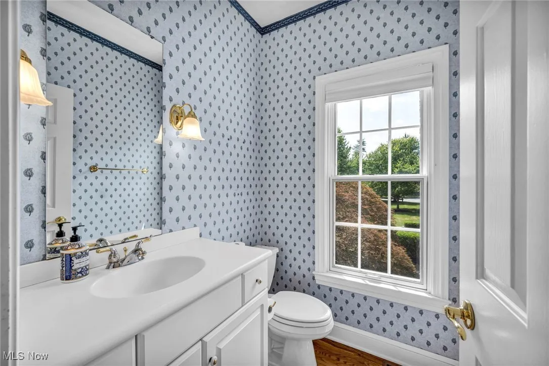 Bathroom featuring wallpapered walls, vanity, and wood finished floors