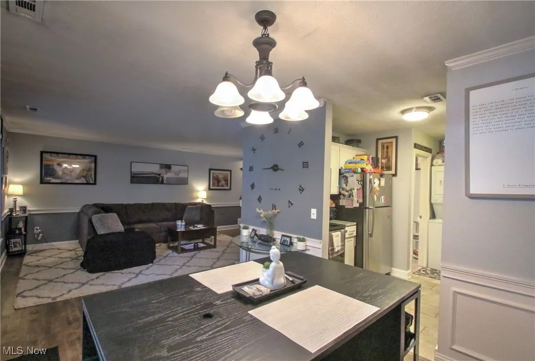 Dining room with a chandelier, crown molding, and stacked washer / drying machine
