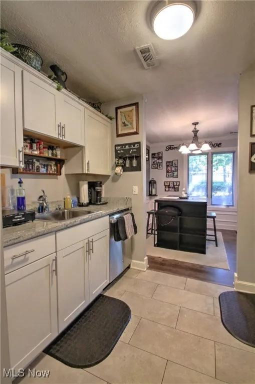 Kitchen featuring white cabinetry, a textured ceiling, light tile patterned flooring, stainless steel dishwasher, and open shelves