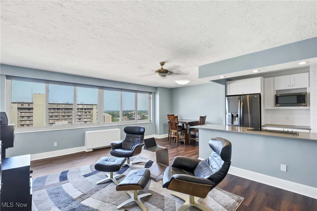 Living room with radiator heating unit, dark wood-type flooring, a textured ceiling, ceiling fan, and recessed lighting