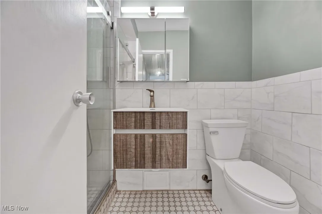Bathroom with tile walls, vanity, and a stall shower