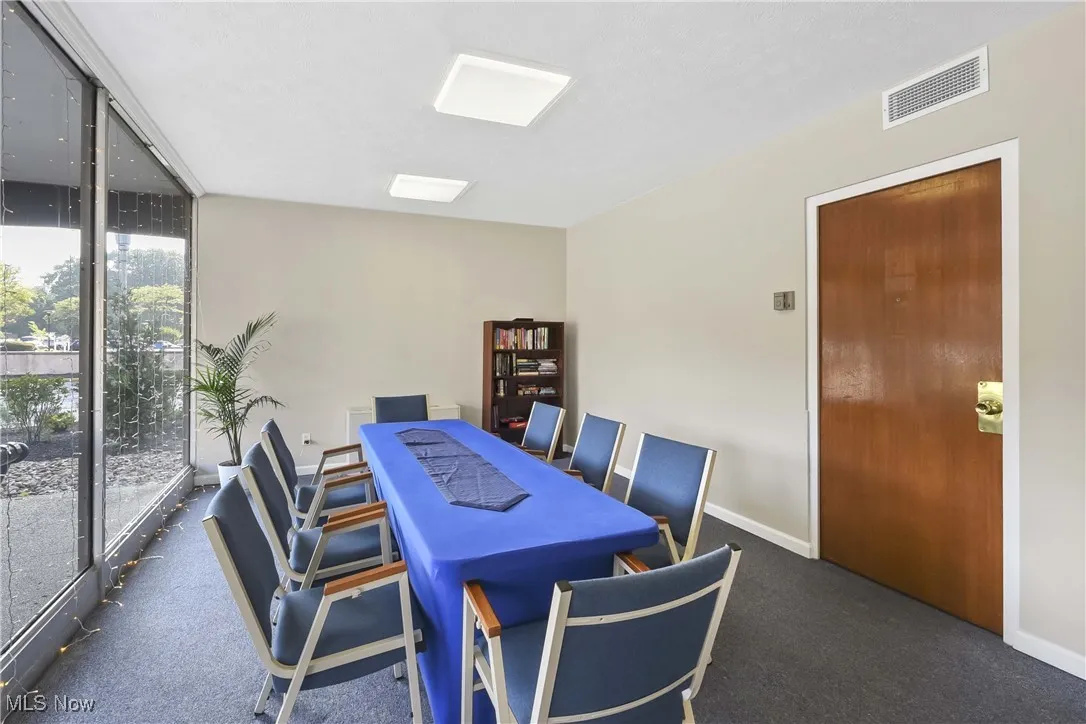 Carpeted dining space featuring a wall of windows and an office area