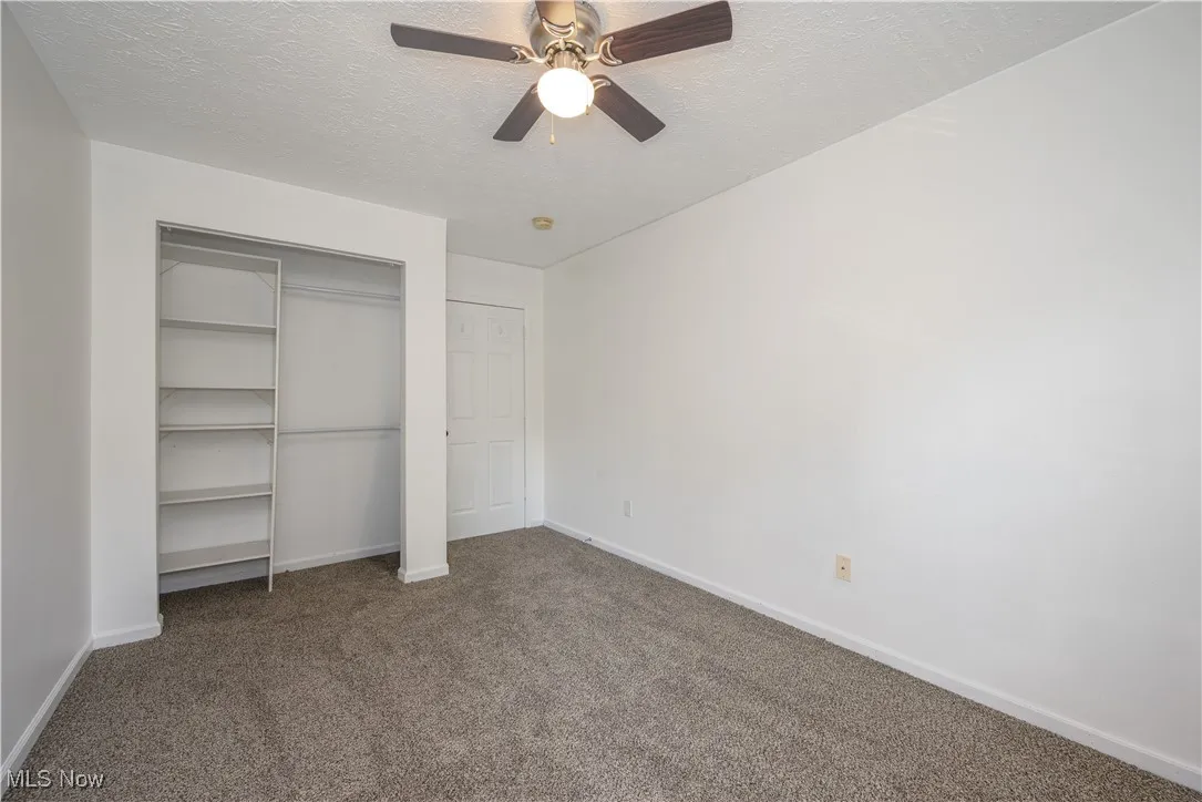 bedroom with a textured ceiling, carpet flooring, a closet, and ceiling fan