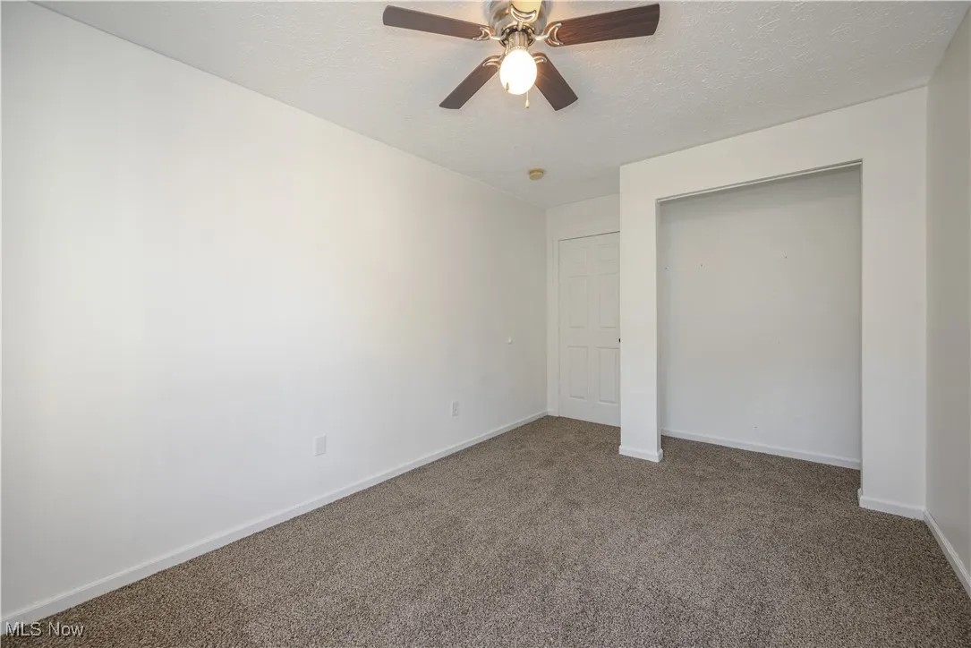 Bedroom featuring carpet flooring, a textured ceiling, a ceiling fan, and a closet