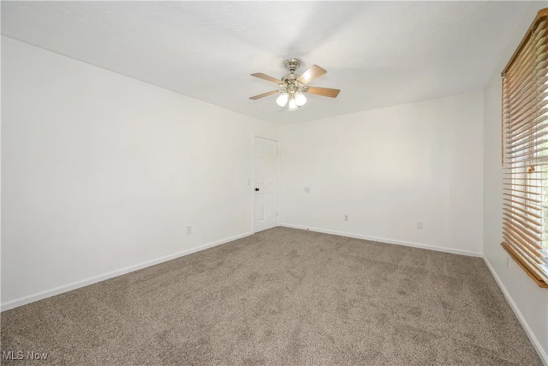 Carpeted empty room featuring a ceiling fan and a textured ceiling