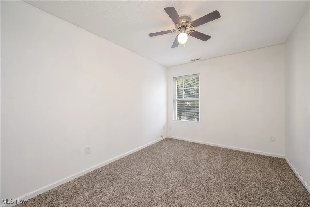 Carpeted empty room with a ceiling fan and a textured ceiling
