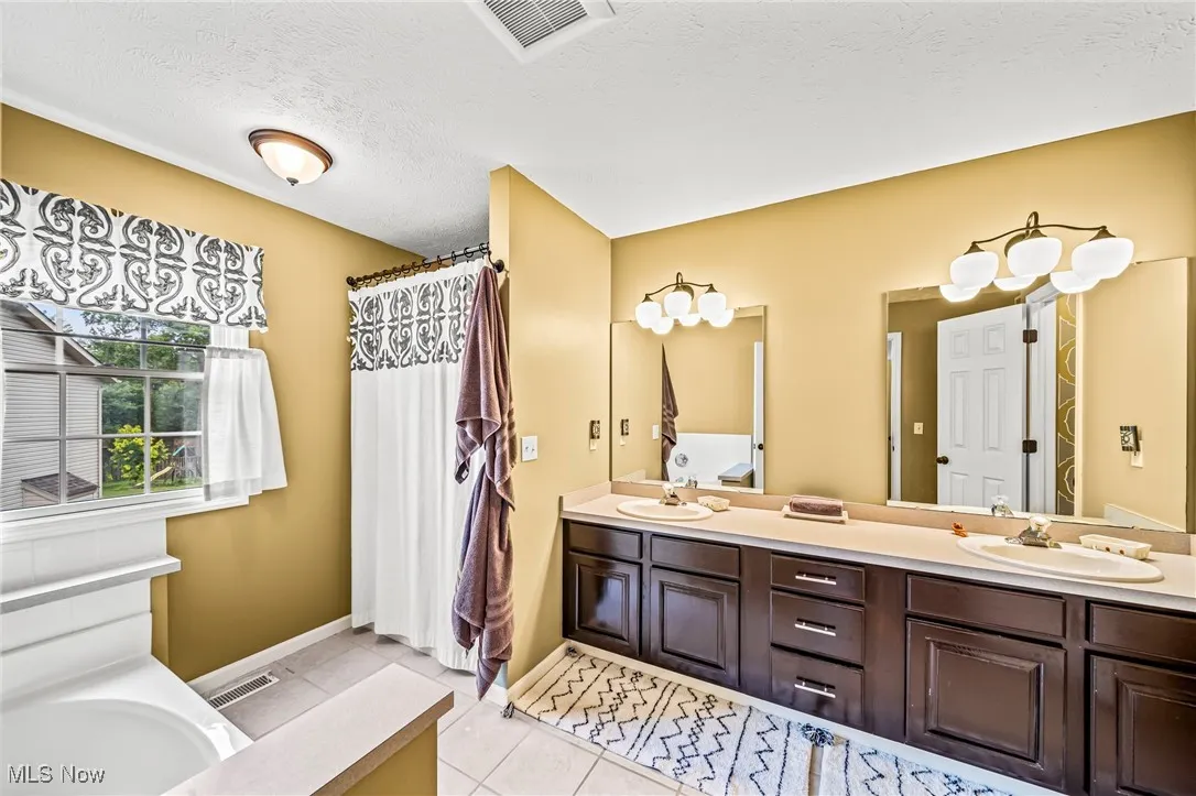 Primary bathroom with double vanities and stand-up shower.