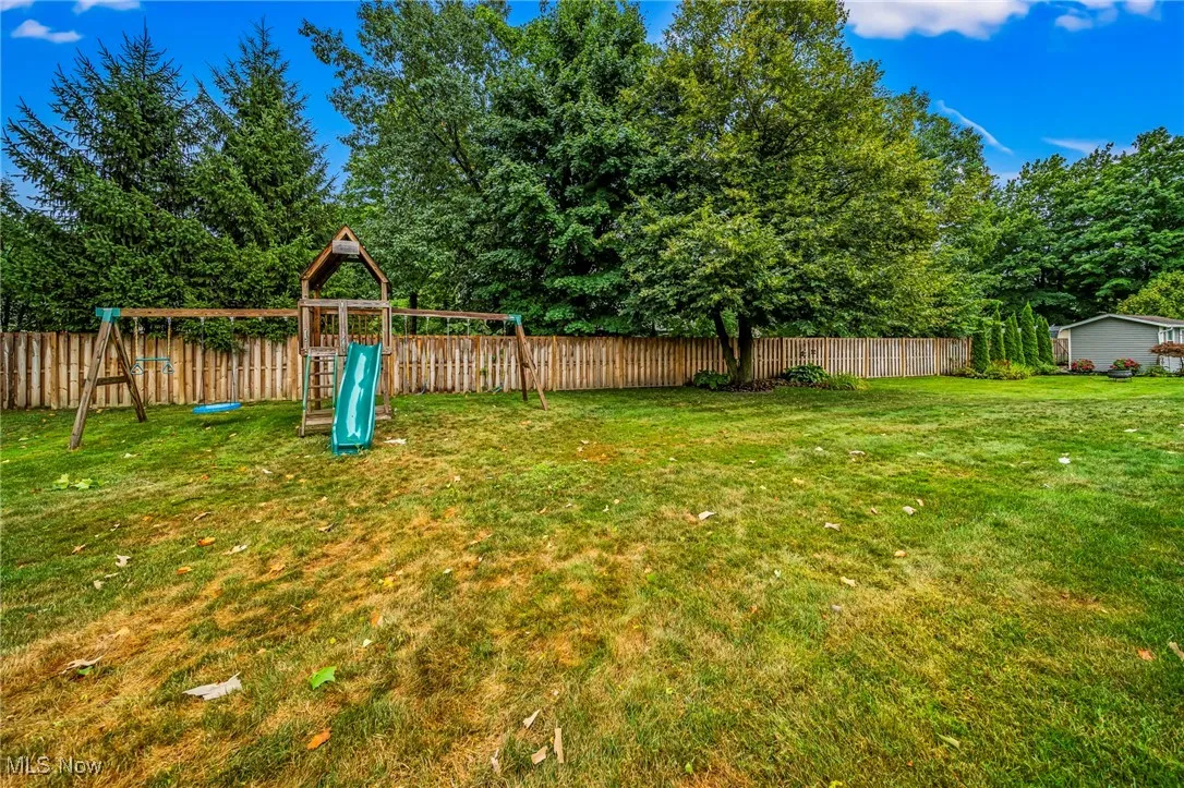 Fenced backyard with a playground.