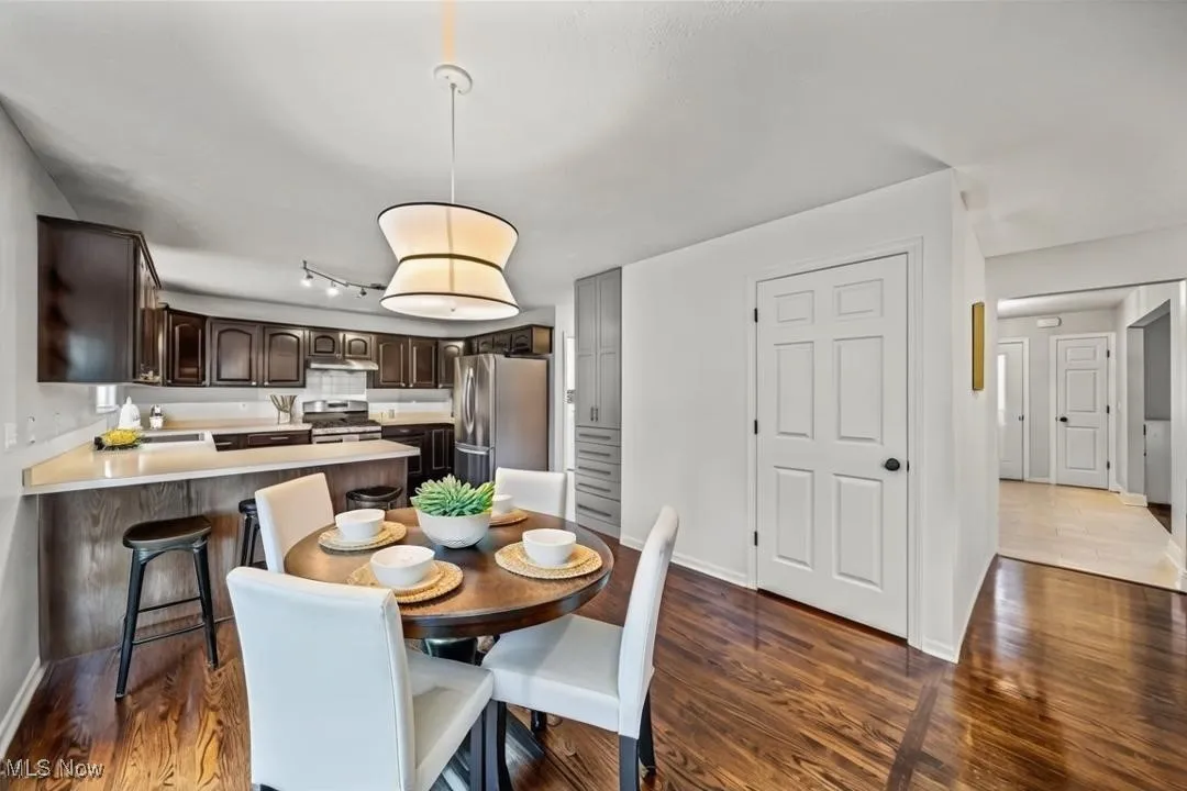 Kitchen featuring wood flooring, dark brown cabinets, appliances with stainless steel finishes, light countertops, and a peninsula. Virtually staged.