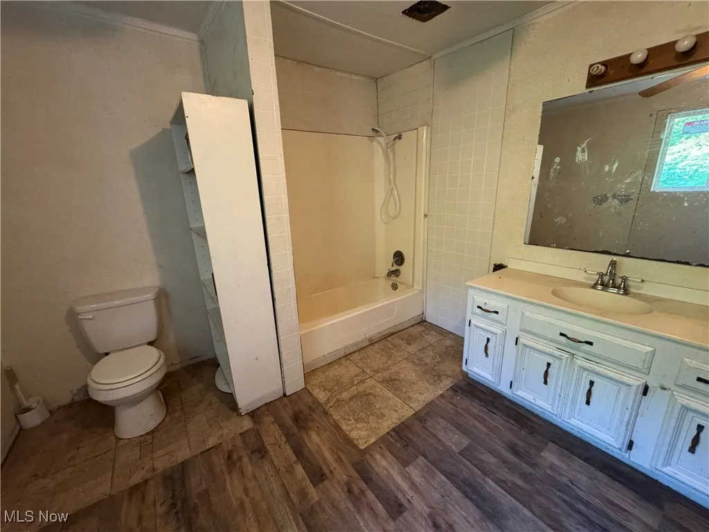 Bathroom featuring bathing tub / shower combination, vanity, ornamental molding, and wood finished floors