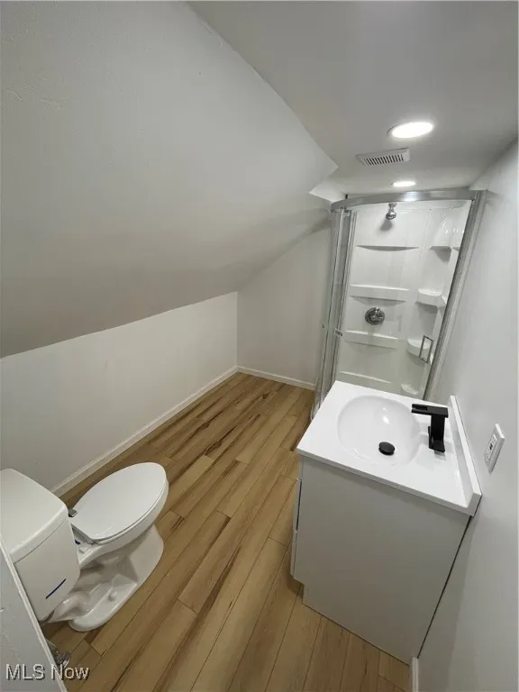 Full bath featuring wood finished floors, vanity, a shower stall, lofted ceiling, and recessed lighting
