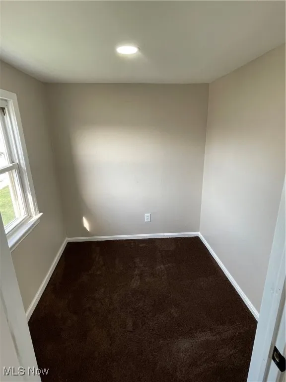 Empty room with dark colored carpet and recessed lighting