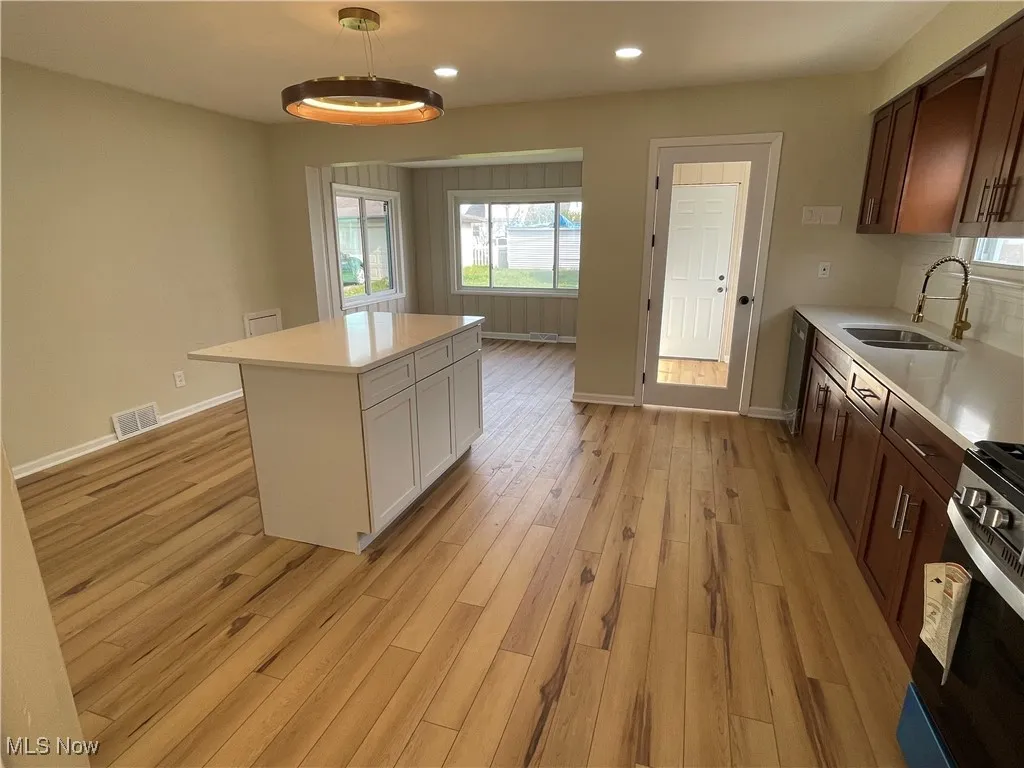 Kitchen with light wood finished floors, light countertops, range, a center island, and recessed lighting