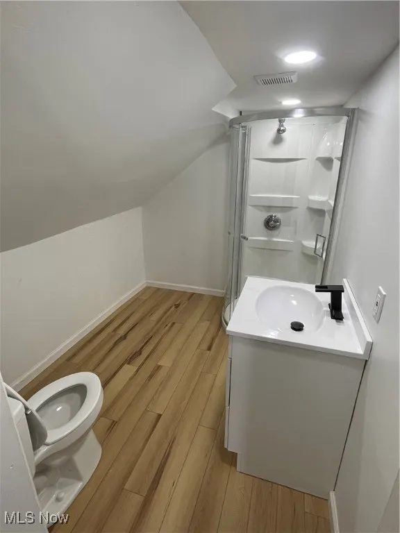 Full bath featuring wood finished floors, a shower stall, vanity, and lofted ceiling