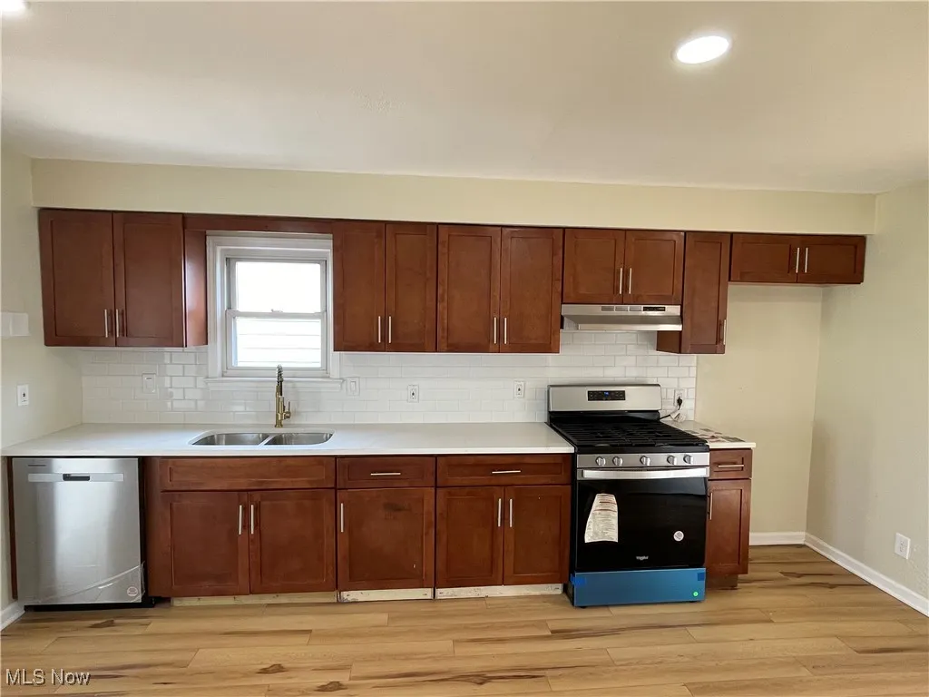 Kitchen featuring appliances with stainless steel finishes, recessed lighting, decorative backsplash, light wood-type flooring, and light countertops