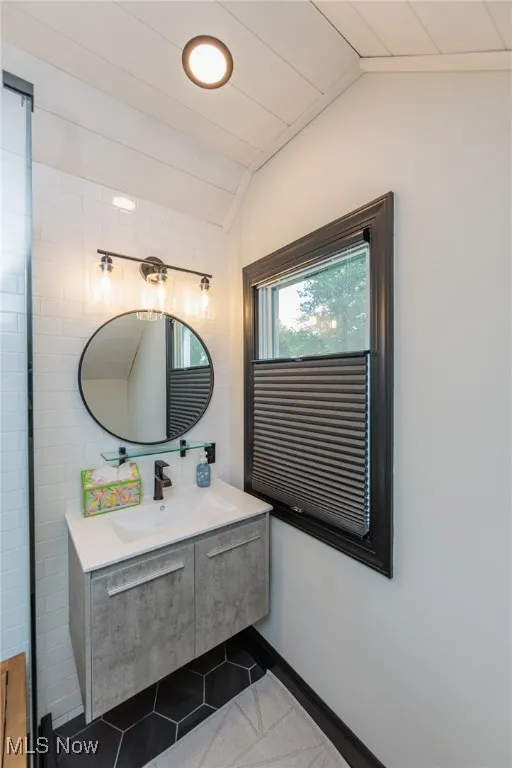 Bathroom with lofted ceiling, tile patterned flooring, and vanity