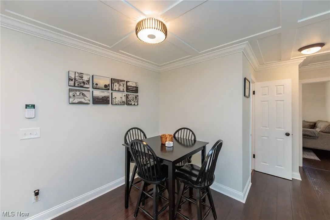 Dining space with dark wood finished floors and crown molding