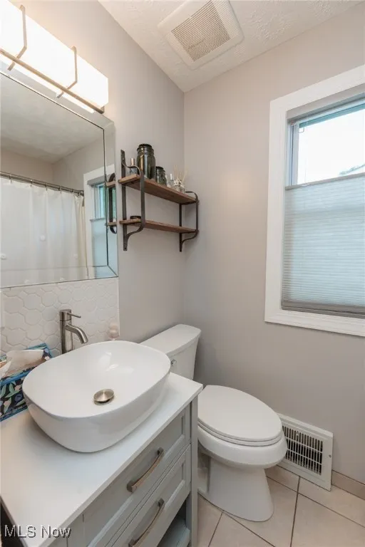 Full bath with backsplash, vanity, tile patterned flooring, and a textured ceiling