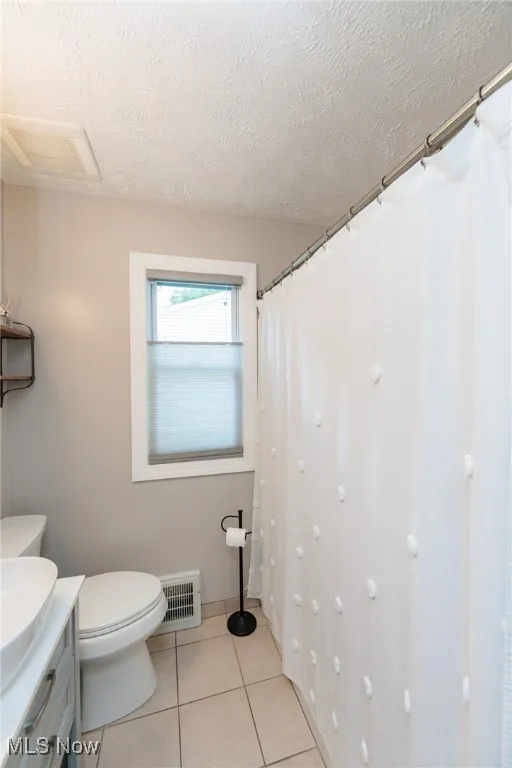 Bathroom featuring a textured ceiling, tile patterned floors, vanity, and curtained shower