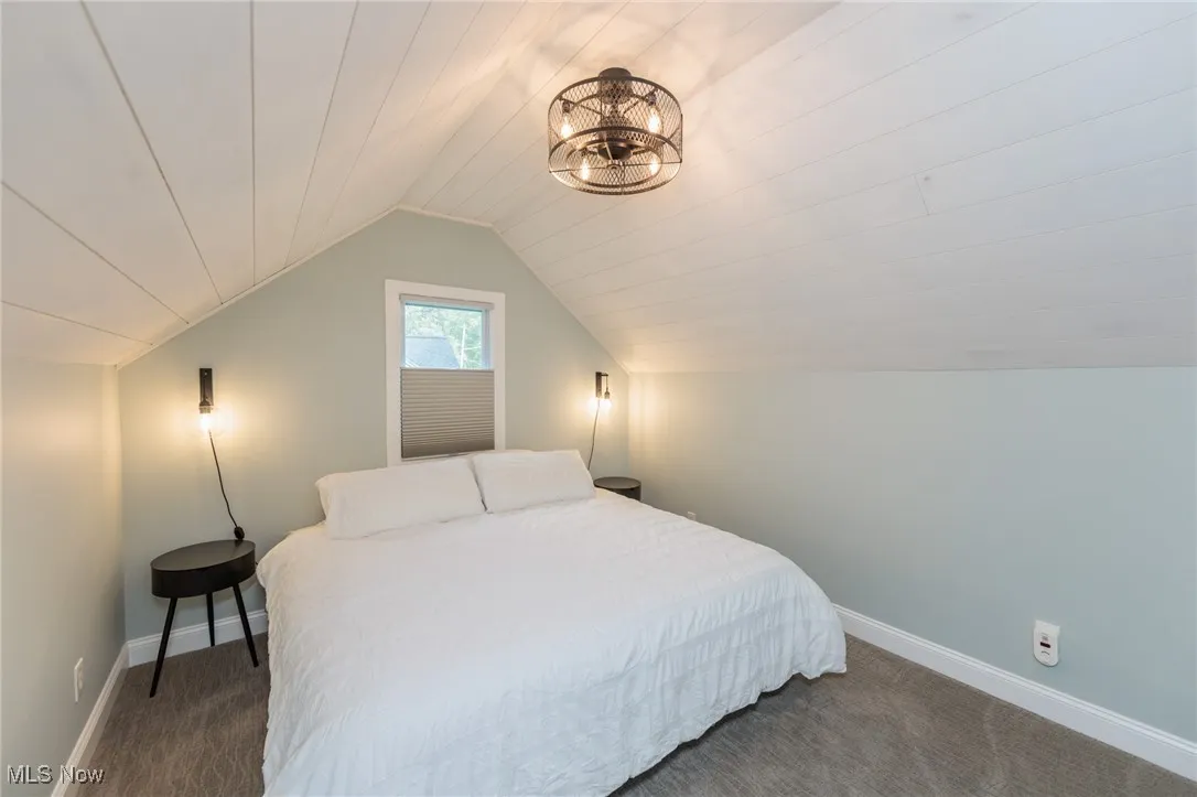 Bedroom with dark carpet and lofted ceiling