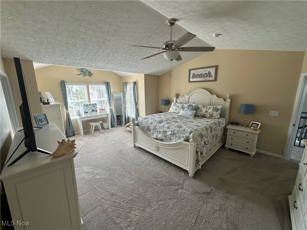 Bedroom with lofted ceiling, carpet flooring, a textured ceiling, and ceiling fan