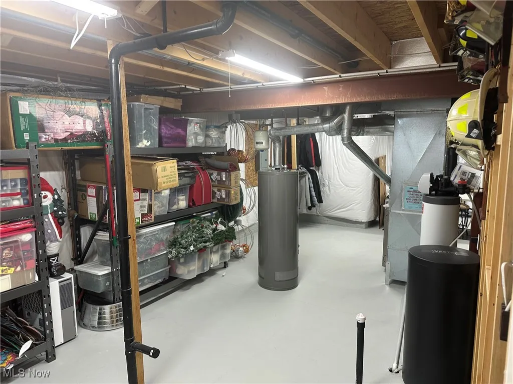 Unfinished below grade area with water heater, a water softener, and heating unit