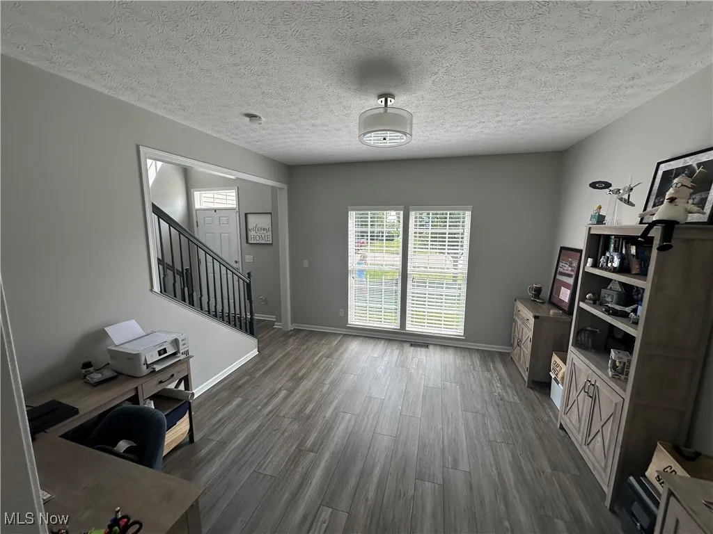 Office space with healthy amount of natural light, a textured ceiling, and dark wood-type flooring