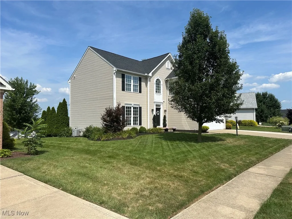 View of front facade with a front yard, a garage, driveway, and roof with shingles