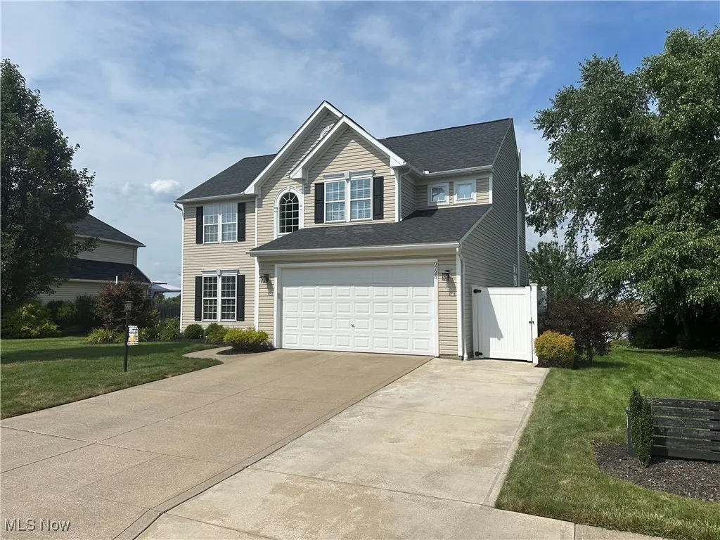 Traditional-style house with concrete driveway, a front lawn, and an attached garage
