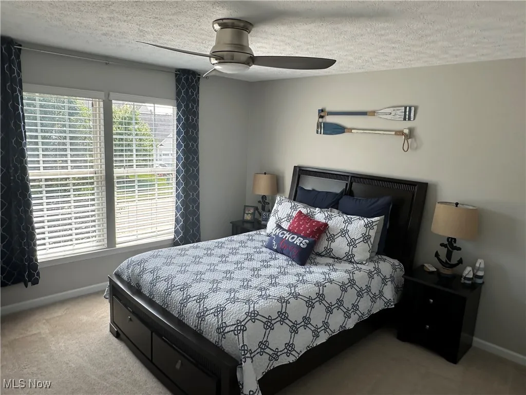 Carpeted bedroom featuring a textured ceiling and ceiling fan