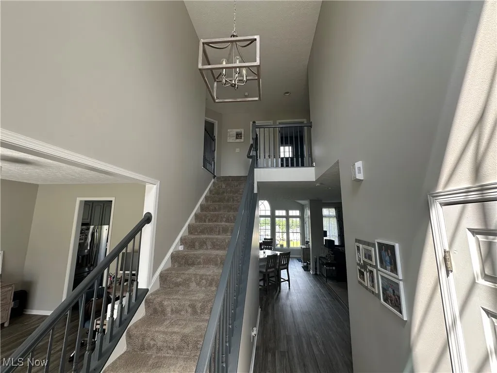 Stairs with a towering ceiling, wood finished floors, a textured ceiling, and a chandelier