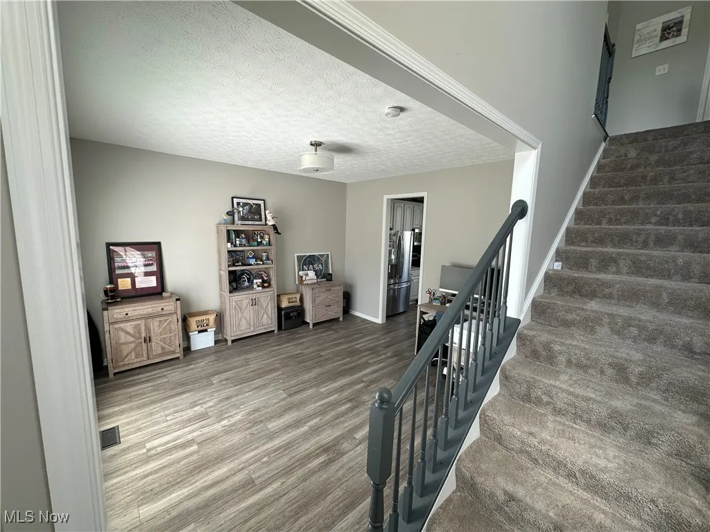Stairs featuring a textured ceiling and wood finished floors