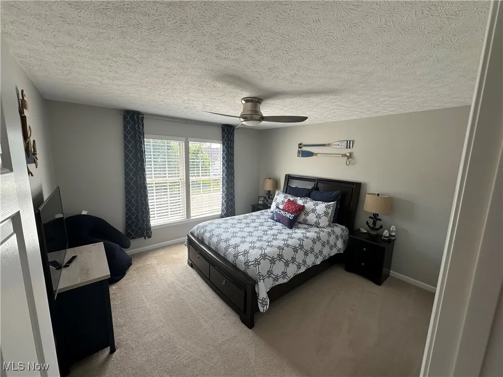 Carpeted bedroom with a textured ceiling and ceiling fan