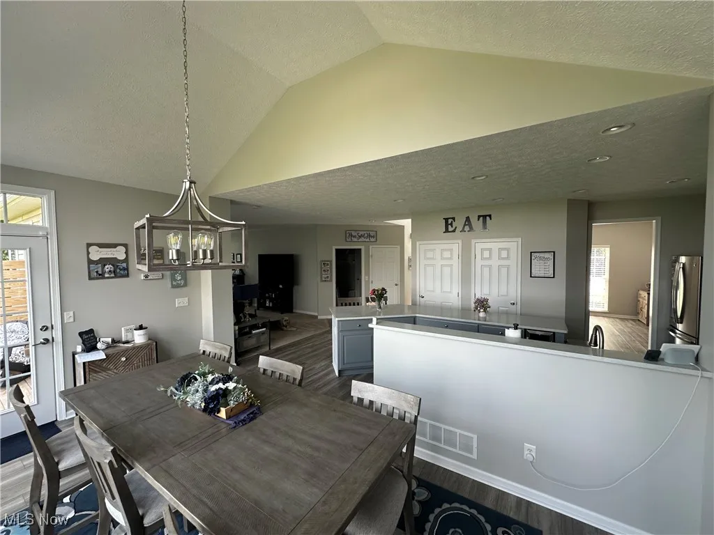 Dining room featuring a textured ceiling, dark wood-style floors, lofted ceiling, and a chandelier