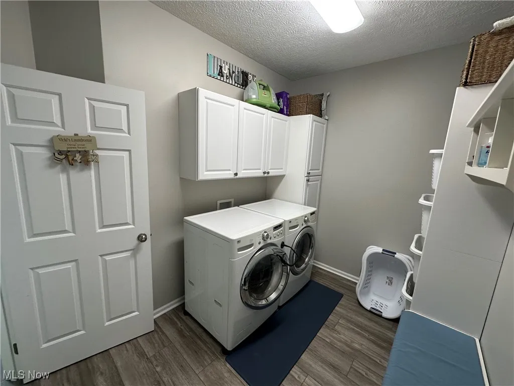Washroom featuring a textured ceiling, independent washer and dryer, cabinet space, and dark wood-style flooring
