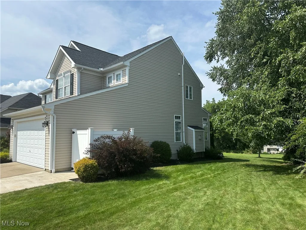 View of side of home with a yard, driveway, and an attached garage