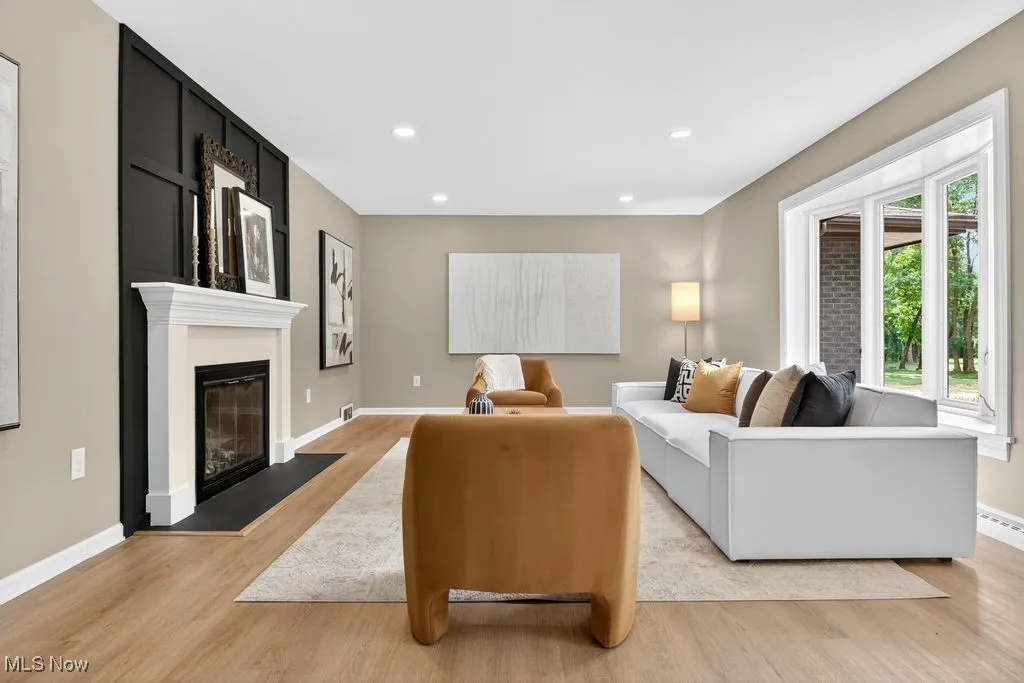 Living room featuring light wood finished floors, a fireplace with flush hearth, and recessed lighting