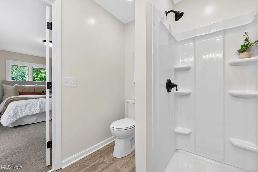 Ensuite bathroom featuring a shower stall and wood finished floors