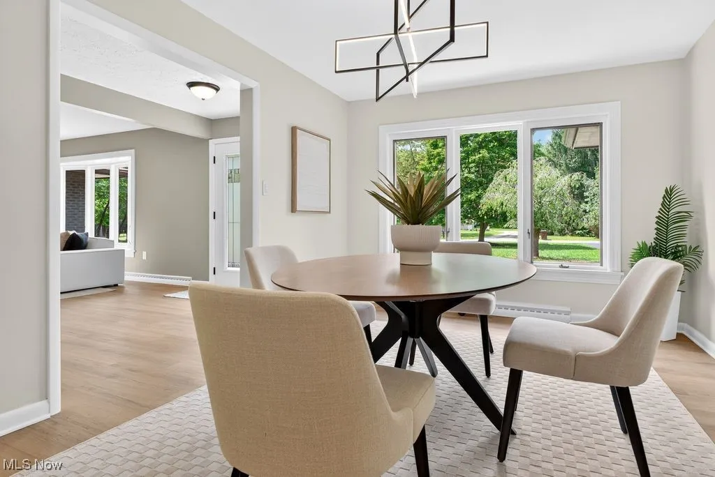 Dining room with light wood-style floors, a chandelier, and baseboard heating